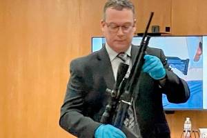 Detective Sgt. Eric Munger of the Clallam County Sheriffs Office prepares to show a semi-automatic rifle presented in the triple-murder trial of Dennis Marvin Bauer. (Paul Gottlieb/Peninsula Daily News)