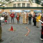 Keith Thorpe/Peninsula Daily News
Noah Smith, director of music ministry at Holy Trinity Lutheran Church, with hat at left, directs a collection of carolers from the church during a performance of holiday songs at the Port Angeles Public Library on Saturday. The church plans to hold virtual and in-person candlelight services on Christmas Eve. For more information, visit www.go2trinity.org.