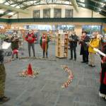 Noah Smith, director of music ministry at Holy Trinity Lutheran Church, with hat at left, directs a collection of carolers from the church during a performance of holiday songs at the Port Angeles Public Library on Saturday. The church plans to hold virtual and in-person candlelight services on Christmas Eve. For more information, visit www.go2trinity.org. (Keith Thorpe/Peninsula Daily News)