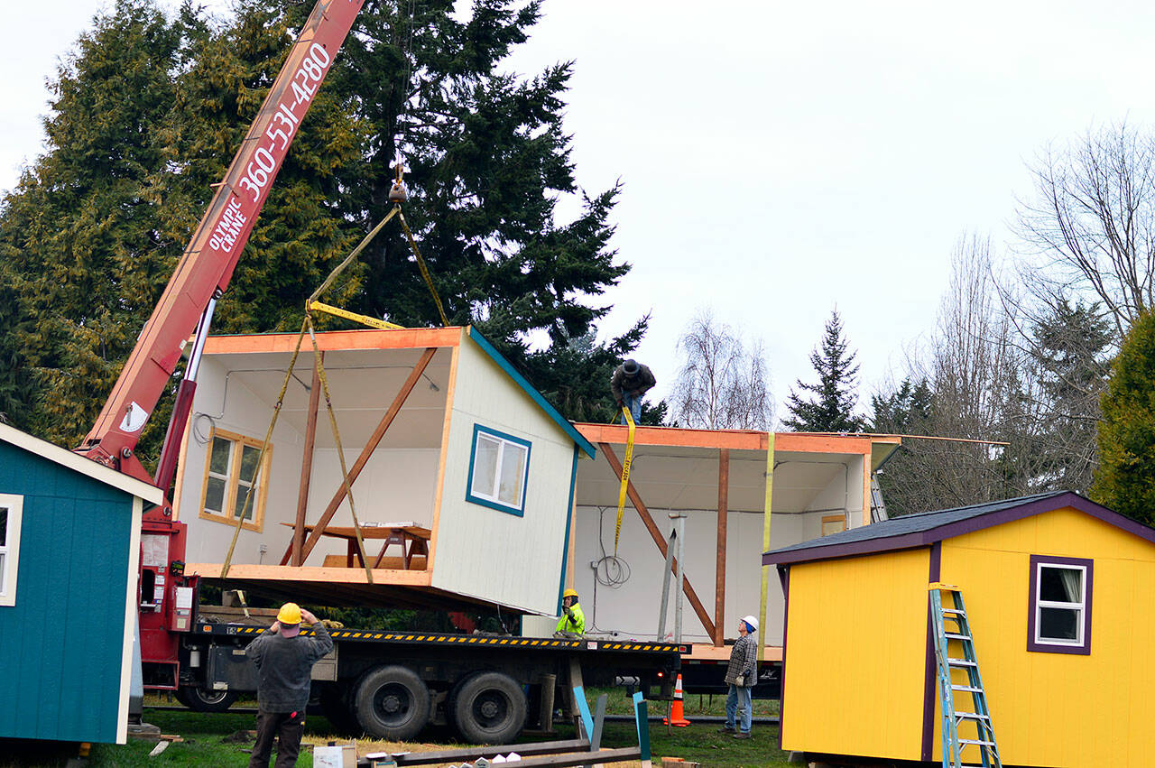 A crane and a crew guide the Pats Place kitchen building  divided in half  onto a truck headed for the new transitional housing village in Port Townsend on Tuesday morning. Bayside Housing & Services hopes to open the self-governed and -contained village next month. (Diane Urbani de la Paz/Peninsula Daily News)