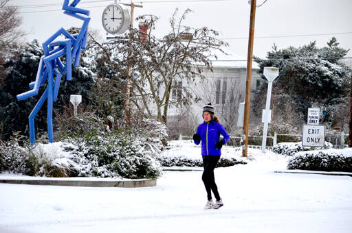 Holly McIlvaine goes for a run up Tyler Street to Aldrichs Market in Port Townsend on Sunday afternoon. The North Olympic Peninsula received reports of up to a foot of snow in places. Two East Jefferson County locations reported 3 to 4 inches to the National Weather Service. (Diane Urbani de la Paz/Peninsula Daily News)