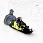 Ned Hammer and his son, Sam Lubinski-Hammer, 7, slide down a popular hill at Stevens Middle School in Port Angeles on Monday morning when the temperature was 19 degrees. (Dave Logan/for Peninsula Daily News)