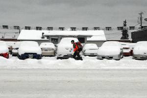 A pedestrian walks past a line of snow-covered vehicles on the lot of Randys Auto Sales in the 800 block of East First Street in Port Angeles on Tuesday. A small amount of overnight snow added to previous snowfalls that began on Christmas Day along most of the North Olympic Peninsula. (Keith Thorpe/Peninsula Daily News)