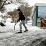 Feiro Marine Life Center Education Manager Rachele Brown clears a layer of newly fallen snow from the front of the building on Thursday at Port Angeles City Pier. (Keith Thorpe/Peninsula Daily News)