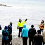 With their backs to Puget Sound, North Olympic Salmon Coalition senior project manager Kevin Long, with black gloves, and stewardship coordinator Nate Roberts give tree-planting volunteers context for their work, (Diane Urbani de la Paz/Peninsula Daily News)