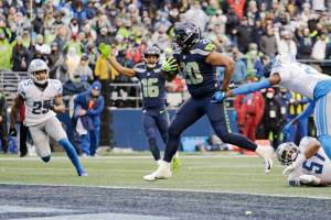 Seattle Seahawks running back Rashaad Penny (20) scores his second touchdown in the first half of an NFL football game against the Detroit Lions, Sunday, Jan. 2, 2022, in Seattle as Seahawks wide receiver Tyler Lockett (16) reacts in the background. (AP Photo/John Froschauer)