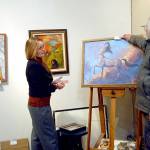 Keith Thorpe/Peninsula Daily News
Bob Stokes, owner of Studio Bob in Port Angeles, right, affixes a sold tag to the oil painting "Sagittarius" by Daniel Miller as Port Angeles artist Sarah Tucker helps on Thursday to prepare for this weekend's "Bring Your Own Art" exhibition.