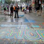 FILE - A sign on the street reads "Welcome to the CHOP" as protesters stand near barricades at the CHOP (Capitol Hill Occupied Protest) zone in Seattle on Tuesday, June 30, 2020. An investigation by the city's police watchdog shows Seattle Police exchanged detailed fake radio transmissions about a nonexistent group of menacing right-wing extremists at a crucial moment during 2020 racial justice protests. Officials said fabricating the group of Proud Boys violated department policies. (AP Photo/Ted S. Warren, File)