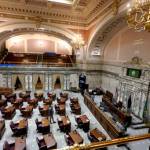 A lone worker walks on the floor of the state Senate last Thursday at the Capitol in Olympia as the room was being prepared for the start of the 2022 legislative session, which opened Monday. The new session will look much like the one a year ago: a limited number of lawmakers on site at the Capitol, and committee hearings being fully remote due to the ongoing COVID-19 pandemic. (Ted S. Warren/The Associated Press)