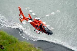 A U.S. Coast Guard helicopter hoists an injured person from the beach at the base of a bluff below 10th and Walker streets on the west side of Port Angeles on Wednesday. (Keith Thorpe/Peninsula Daily News)