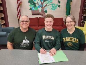Aiden Henninger of Sequim, with his father, Ray, left and mother Ann Marie Henninger, signs to play soccer at Franciscan University in Steubenville, Ohio.