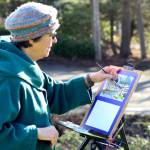 Madeline Nelson of Port Townsend works in watercolors and bright sun on the grass outside the Jefferson County Courthouse. The plein air painter typically spends just an hour finishing a piece before her hands get too cold. (Diane Urbani de la Paz/Peninsula Daily News)