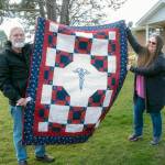 Doc and Valkyrie Ferguson hold up the Quilts of Valor quilt given to Valkyrie earlier this month. (photo by Chris Bates)