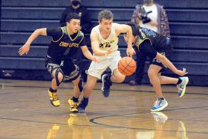 Forks Logan Olson (24) drives between Warrior defenders Mickey Lara (left) and Emanual Mowat Wednesday night in Forks where the Spartans defeated the Chief Leschi Warriors 68 to 54.  Photo by Lonnie Archibald.