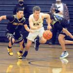 Forks Logan Olson, center, drives between Chief Leschi defenders Mickey Lara, left, and Emanual Mowat during the Spartans 68-54 win over the Warriors on Wednesday. (Lonnie Archibald/for Peninsula Daily News)