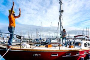 On Mondays sun-drenched skies, Ben Doerr of Bainbridge Island directs a crane operator while Port Townsend rigger Sean Ranking, from Northwest Sails and Canvas, guides the mast into Doerrs 44-foot Pierson Countess motor sailer. Doerr did a refit on his charter boat, True, including updates and wiring. (Steve Mullensky/for Peninsula Daily News)