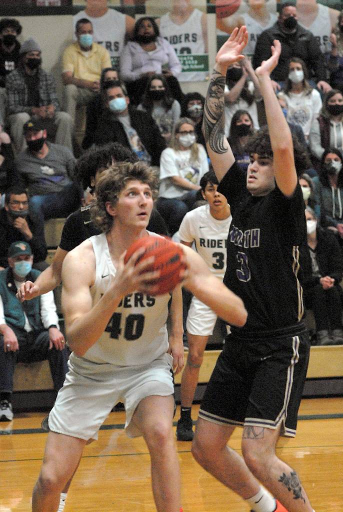 Keith Thorpe/Peninsula Daily News Port Angeles John Vaara, left, looks for the hoop as North Kitsaps Aiden Olmstead defends the lane on Thursday night in Port Angeles.