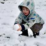Grayson Haag, 3, helps make a small snowman Thursday morning from his home on Peabody Street. His mom, Amber Garbrick, helped with the fun in the snow. (Dave Logan/for Peninsula Daily News)