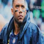 A pedestrian walks past a photo of Seattle Seahawks quarterback Russell Wilson at Lumen Field, Tuesday, March 8, 2022, in Seattle. The Denver Broncos agreed to send a massive haul of players and draft picks to the Seattle Seahawks in a trade for Wilson, two people familiar with the negotiations confirmed to The Associated Press on Tuesday. The blockbuster trade, which is pending Wilson passing a physical, can't become official until the start of the new league year on March 16, 2022. (AP Photo/Ted S. Warren)