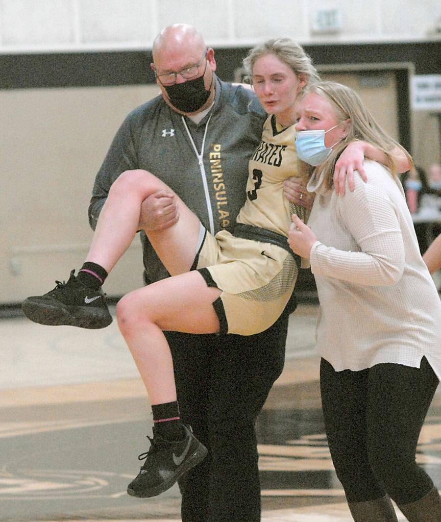 Peninsulas Millie Long is helped from the court by assistant coach Mike Knowles, left, and head coach Alison Crumb after Long injured her ankle in the closing minutes of Wednesdays game against Shoreline. (Keith Thorpe/Peninsula Daily News)