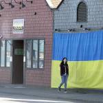 Shawna Small walks on Marine Drive in Port Angeles past a large Ukrainian flag on the outside of Mister Buds, which owner Malik Atwater put up recently along with the U.S. flag he has flown for many years. The flag was hand-sewn by Vivian Wai, Atwaters wife, after the two discussed how to support the Ukrainians as they fight against the invasion of the country launched by Russia on Feb. 24. We felt helpless to do anything to help, Atwater said, adding that it was Wai who came up with the idea. (Dave Logan/for Peninsula Daily News)