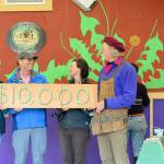 To mark the Rotary Club of Port Townsend's $10,000 gift to the Community Boat Project -- which is constructing tiny homes for local farmworkers -- boat project director Wayne Chimenti, far right, and shop organizer Gillian Kenagy, second from right, quickly painted a "check" on a piece of wood. Rotarian Carla Caldwell, far left, and club president Jim Cunnington were among the volunteers who joined a work party toward finishing the project's latest wooden tiny house last week.  Diane Urbani de la Paz/Peninsula Daily News