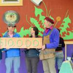 To mark the Rotary Club of Port Townsends $10,000 gift to the Community Boat Project  which is constructing tiny homes for local farmworkers  boat project director Wayne Chimenti, far right, and shop organizer Gillian Kenagy, second from right, quickly painted a check on a piece of wood. Rotarian Carla Caldwell, far left, and club president Jim Cunnington were among the volunteers who joined a work party toward finishing the projects latest wooden tiny house last week. (Diane Urbani de la Paz/Peninsula Daily News)