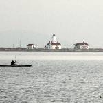 Ken Lincoln of Port Townsend kayaks across Dungeness Bay against a backdrop of the New Dungeness Lighthouse on Saturday north of Sequim. Lincoln said he was paddling out from Cline Spit to meet a group of other kayakers who were putting in at Port Williams. (Keith Thorpe/Peninsula Daily News)