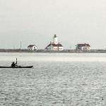 Ken Lincoln of Port Townsend kayaks across Dungeness Bay against a backdrop of the New Dungeness Lighthouse on Saturday north of Sequim. Lincoln said he was paddling out from Cline Spit to meet a group of other kayakers who were putting in at Port Williams. (Keith Thorpe/Peninsula Daily News)