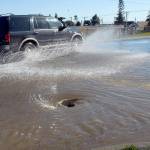 Traffic splashes along East Lauridsen Boulevard as water from a main break flows into a storm drain at South Chase Street on Wednesday after a 6-inch water line burst in the 200 block of East Orcas Avenue in Port Angeles. (Keith Thorpe/Peninsula Daily News)