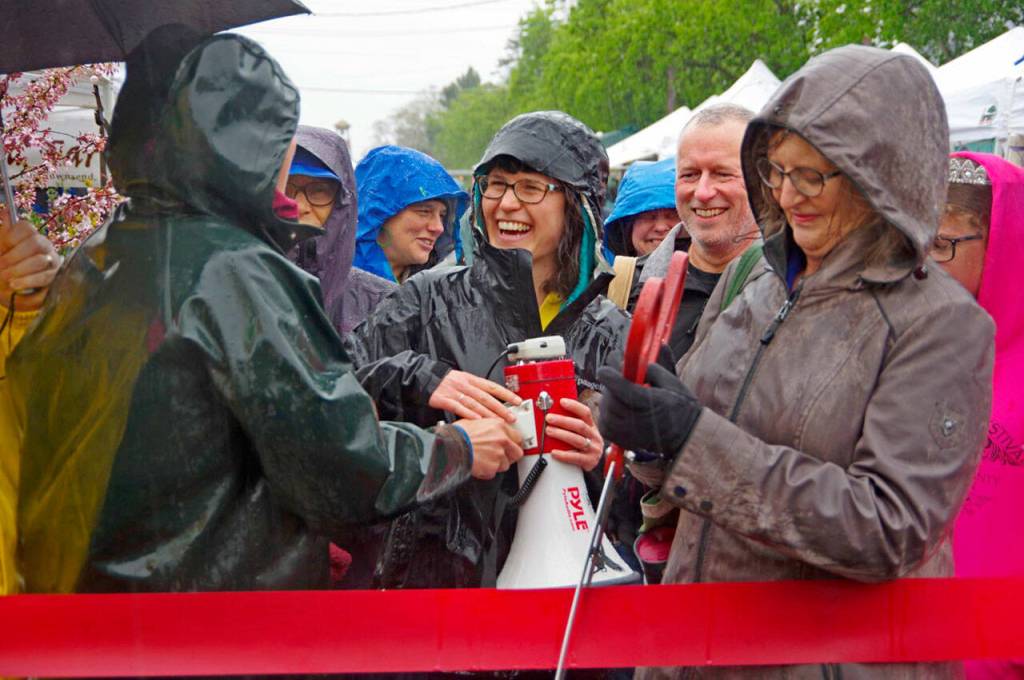 Opening day at the Port Townsend Farmers Market in 2019 was festive, crowded and wet as market manager Amanda Milholland, center, and then-Mayor Deborah Stinson cut the ribbon. (Jefferson County Farmers Markets)