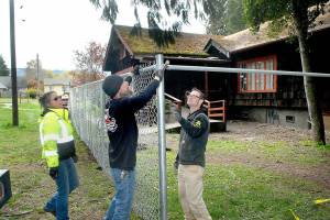 Keith Thorpe/Peninsula Daily News
Port Angeles Parks and Recreation Department workers, from left, Brooke Keohokalole, Darryl Anderson and Eli Hammel install a chain link fence around a portion of the Campfire Clubhouse at Jessie Webster Park on Wednesday. The fence is part of an effort to keep transients from camping on the covered porch of the building, which is used for a variety of community events.
