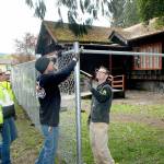 Port Angeles Parks and Recreation Department workers, from left, Brooke Keohokalole, Darryl Anderson and Eli Hammel install a chain link fence around a portion of the Campfire Clubhouse at Jessie Webster Park on Wednesday. (Keith Thorpe/Peninsula Daily News)