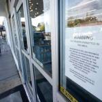 A sign warns that firearms are prohibited at Mary Mart, a marijuana store, Tuesday, April 19, 2022, in Tacoma, Wash., as armed security guard Austin MacMath stands watch outside at left. A surge in robberies at licensed cannabis shops in Washington state is helping fuel a renewed push for federal banking reforms that would make the cash-dependent stores a less appealing target. (AP Photo/Ted S. Warren)