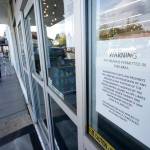 A sign warns that firearms are prohibited at Mary Mart, a marijuana store, Tuesday in Tacoma as armed security guard Austin MacMath stands watch outside at left. A surge in robberies at licensed cannabis shops in Washington state is helping fuel a renewed push for federal banking reforms that would make the cash-dependent stores a less appealing target. (AP Photo/Ted S. Warren)