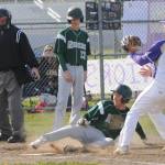 With teammate Hunter Robinson (13) looking on, Port Angeles' Colton Romero slides safely into home ahead of the tag of Sequim pitcher Connor Bear in Sequim on Monday. (Michael Dashiell/Olympic Peninsula News Group)