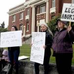 Reproductive rights supporters, from left, Tawny Bagby, Jill Coughenour and Janet Ferris, all of Port Angeles, hold signs protesting the possible overturning of the Roe v. Wade by the U.S. Supreme Court during a gathering on Tuesday in front of the Clallam County Courthouse. About 60 people took part in the event. (Keith Thorpe/Peninsula Daily News)