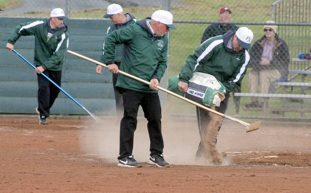 Port Angeles coaches and assistants spread drying agent on the infield at the Dry Creek School softball field after a drenching rain muddied the playing surface in the first inning on Thursday against North Kitsap.
Keith Thorpe/Peninsula Daily News