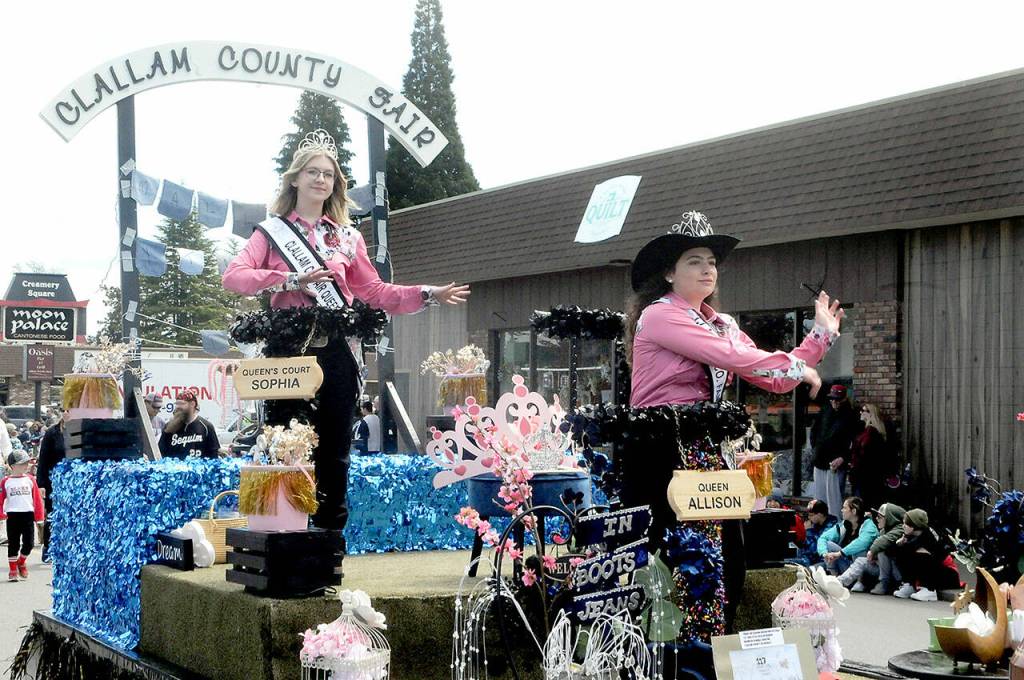 Clallam County Fair Queen Allison Pettit, front, and Queens Court Sophia Lawson ride the fairs parade float on Saturday in Sequim. Junior Royalty Kendall Adolphe rode in a separate car as an honor for designing the 2022 Irrigation Festival pin. (Keith Thorpe/Peninsula Daily News)