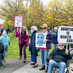 Linda Martin, center, from Port Townsend, stands beside her husband Mike Cornforth on the corner of Kearney and state Highway 20 in Port Townsend. Martin, with PT Indivisible, collaborated with Planned Parenthood, the American Civil Liberties Union and Womens March to stage a rally on Saturday to protest the possible U.S. Supreme Court decision to overturn the 50-year-old Roe v Wade decision guaranteeing the right to abortion. About 250 people from as far away as Seattle and Sequim took part in the rally. (Steve Mullensky/for Peninsula Daily News)