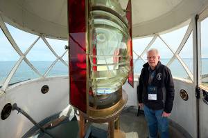 Dick Richardson, volunteer coordinator of the U.S. Light House Society, shows off the 1880s French made fresnel lens at the top of the Point Wilson Light at Fort Worden State Park. The society is the caretaker of the lighthouse, under a license from the U.S. Coast Guard. Public tours are conducted from 11 a.m. to 4 p.m. on Saturdays and Sundays. Because of liability issues and Coast Guard regulations, the top floor, where the lens is located, will be off limits. (Steve Mullensky/for Peninsula Daily News)