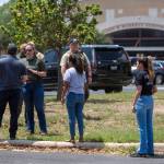 A law enforcement officer speaks with people outside Uvalde High School after shooting a was reported earlier in the day at Robb Elementary School on Tuesday in Uvalde, Texas. (William Luther/The San Antonio Express-News via AP)