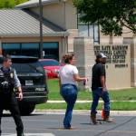 A law enforcement officer helps people cross the street at Uvalde Memorial Hospital after a shooting was reported earlier in the day at Robb Elementary School on Tuesday in Uvalde, Texas. (Billy Calzada/The San Antonio Express-News via AP)