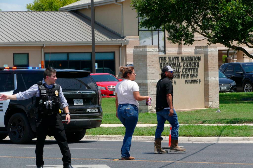 A law enforcement officer helps people cross the street at Uvalde Memorial Hospital after a shooting was reported earlier in the day at Robb Elementary School on Tuesday in Uvalde, Texas. (Billy Calzada/The San Antonio Express-News via AP)