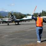 Tom Wayne Duke of Langley directs traffic as a North American SNJ-5 Texan based in Diamond Point taxies into a parking spot on Saturday at William R. Fairchild International Airport as part of Armed Forces & Public Safety Airport Appreciation Day and Fly-in. The event featured a variety of modern and vintage aircraft, flying demonstrations, public saftey displays and Young Eagles flights for children. (Keith Thorpe/Peninsula Daily News)