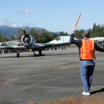 Tom Wayne Duke of Langley directs traffic as a North American SNJ-5 Texan based in Diamond Point taxies into a parking spot on Saturday at William R. Fairchild International Airport as part of Armed Forces & Public Safety Airport Appreciation Day and Fly-in. The event featured a variety of modern and vintage aircraft, flying demonstrations, public saftey displays and Young Eagles flights for children. (Keith Thorpe/Peninsula Daily News)