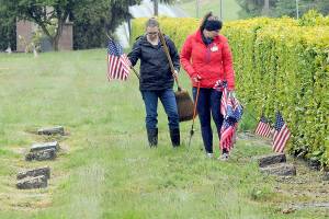 Monica Reynolds, a prospective member of the Daughters of the American Revolution, left, and Lindsey Christianson, a member of the organizations Port Angeles-based Michael Trebert Chapter, locate graves of veterans for adornment with American flags on Saturday for Mondays Memorial Day ceremony at 9:30 a.m. at Mount Angeles Memorial Park, 45 Monroe Road in Port Angeles. (Keith Thorpe/Peninsula Daily News)