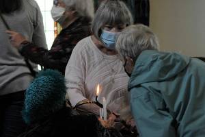 Pat Rublaitus helps light candles for a prayer service on Friday inside St. Lukes Episcopal Church in Sequim for the victims of the Robb Elementary School shooting in Uvalde, Texas. About 40 people attended to pray and sing for the teachers and students and their families. Participants were encouraged to write prayers on cloth strips to be attached to a fence outside the church. The interfaith service was sponsored by St. Lukes, Dungeness Valley Lutheran Church and Trinity United Methodist Church. (Matthew Nash/Olympic Peninsula News Group)