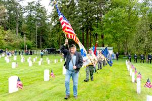 Dave Harrah, a former chaplain with American Legion Post 26 in Port Townsend, leads the color guard of scouts from Troop 1480 in Chimacum, to start the Memorial Day service at Fort Worden Military Cemetery on Monday. (Steve Mullensky/for Peninsula Daily News)