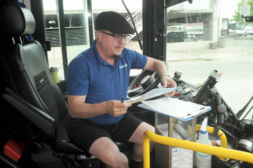 Clallam Transit driver Elliot Boughen-Caldwell looks over a card identifying acceptable admissions to Olympic National Park before setting off on the first scheduled bus to Hurricane Ridge on Wednesday. (Keith Thorpe/Peninsula Daily News)